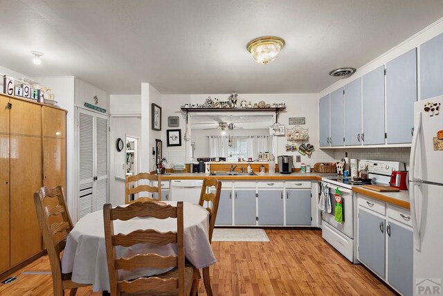 kitchen with ceiling fan, white appliances, a sink, visible vents, and light wood-type flooring