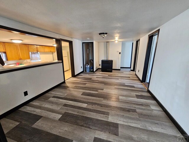 unfurnished living room with a textured ceiling, dark wood-type flooring, and baseboards