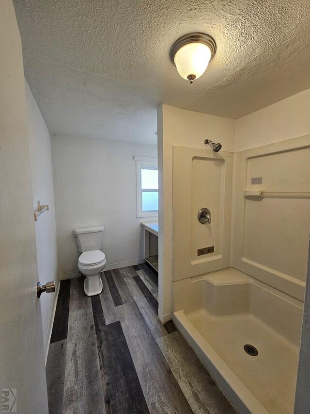 full bath with a textured ceiling, a shower, wood finished floors, and toilet