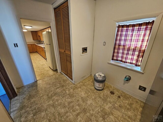 hallway with baseboards, a sink, and light floors