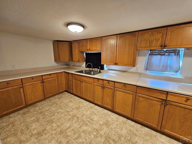 kitchen featuring brown cabinetry, light countertops, a sink, and light floors