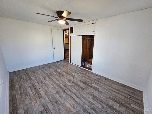 unfurnished bedroom featuring ceiling fan, a closet, dark wood finished floors, and baseboards