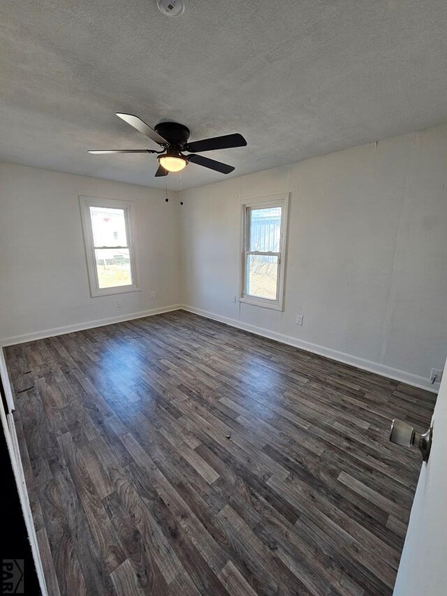 unfurnished room featuring dark wood-style flooring, ceiling fan, a textured ceiling, and baseboards