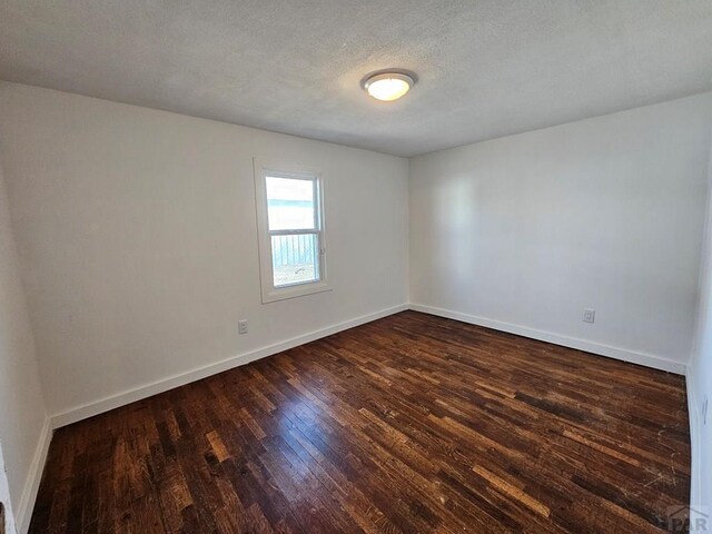 spare room with dark wood-style floors, baseboards, and a textured ceiling