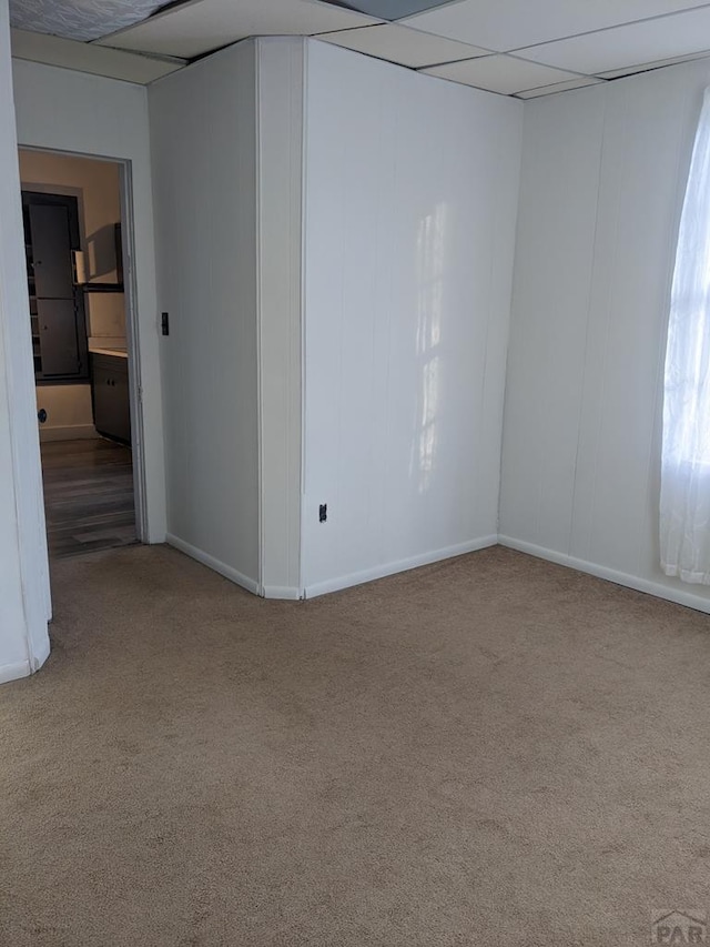carpeted empty room with a drop ceiling