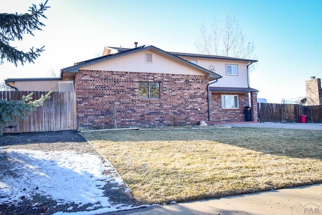 view of front of property with a patio area, brick siding, a front yard, and fence