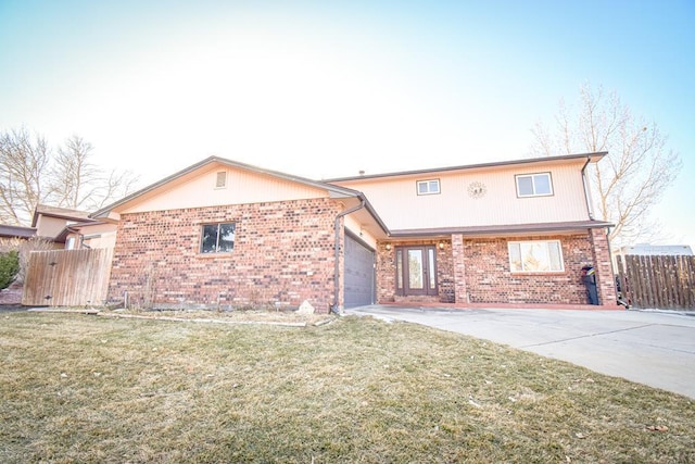 traditional-style home with a garage, brick siding, fence, concrete driveway, and a front yard