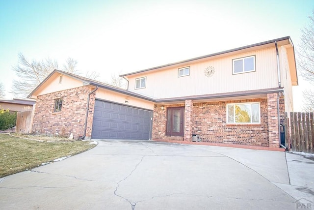 traditional-style house with driveway, an attached garage, fence, and brick siding