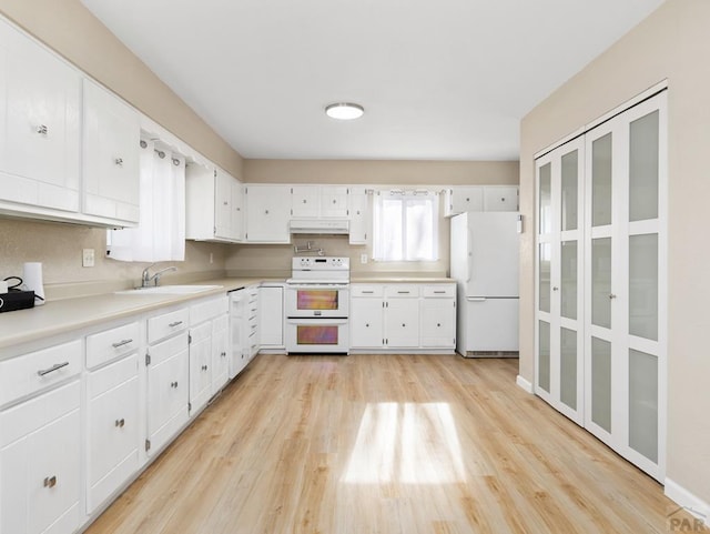 760 Crystal Ln, Pueblo, CO 81006 - kitchen featuring light countertops, light wood-style flooring, white cabinetry, a sink, and white appliances
