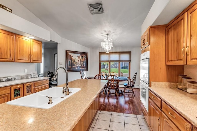 29 Portero Dr, Pueblo, CO 81005 - kitchen with a sink, light tile patterned flooring, light countertops, vaulted ceiling, and brown cabinets