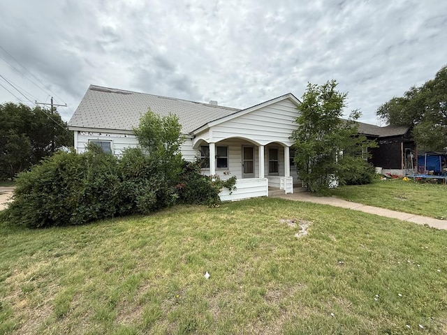309 W 13th St, Eads, CO 81036 - view of front of house featuring covered porch, a front lawn, and a trampoline