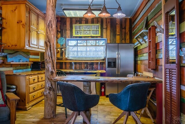 361 Crystal Peak Rd, Florissant, CO 80814 - interior space with stainless steel fridge with ice dispenser, light wood finished floors, wood walls, and pendant lighting