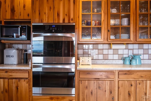 361 Crystal Peak Rd, Florissant, CO 80814 - kitchen with black microwave, double oven, light countertops, decorative backsplash, and glass insert cabinets