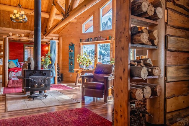 361 Crystal Peak Rd, Florissant, CO 80814 - living area featuring wood finished floors, a wood stove, beam ceiling, high vaulted ceiling, and a notable chandelier