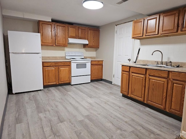 kitchen with brown cabinets, light countertops, a sink, white appliances, and under cabinet range hood