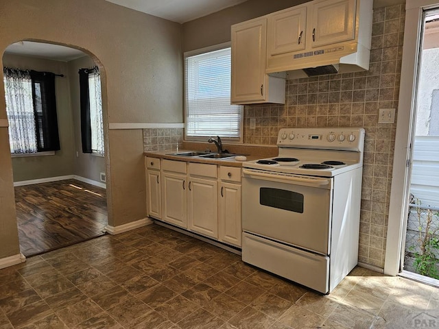 kitchen featuring arched walkways, white range with electric cooktop, light countertops, a sink, and under cabinet range hood