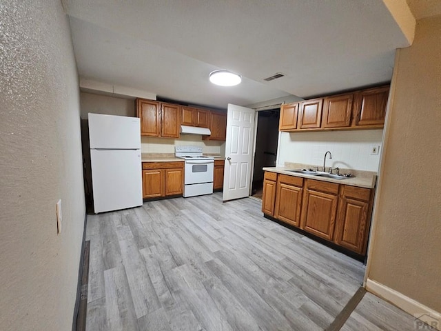 kitchen with white appliances, visible vents, light countertops, under cabinet range hood, and a sink