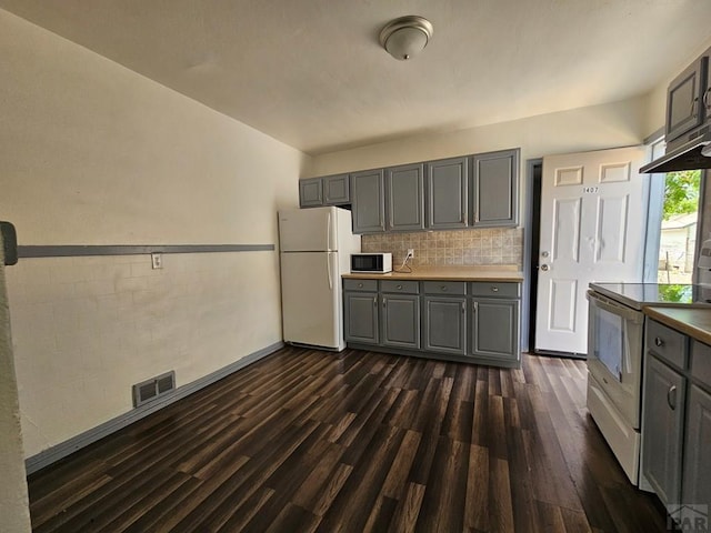 kitchen featuring white appliances, visible vents, dark wood finished floors, gray cabinets, and backsplash