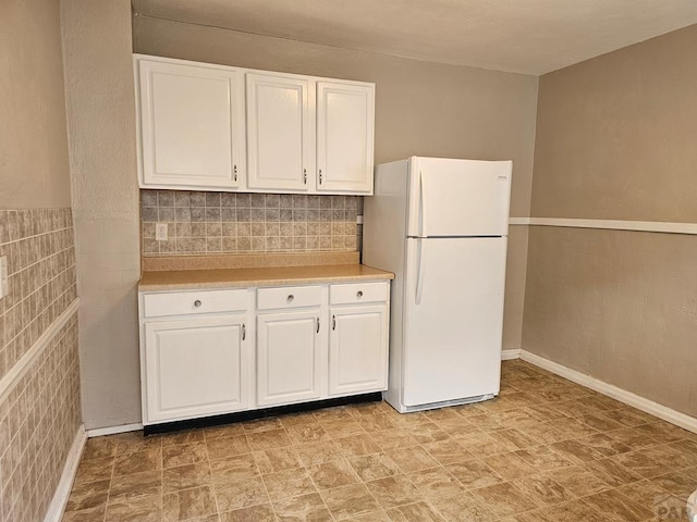 kitchen with light countertops, freestanding refrigerator, and white cabinets