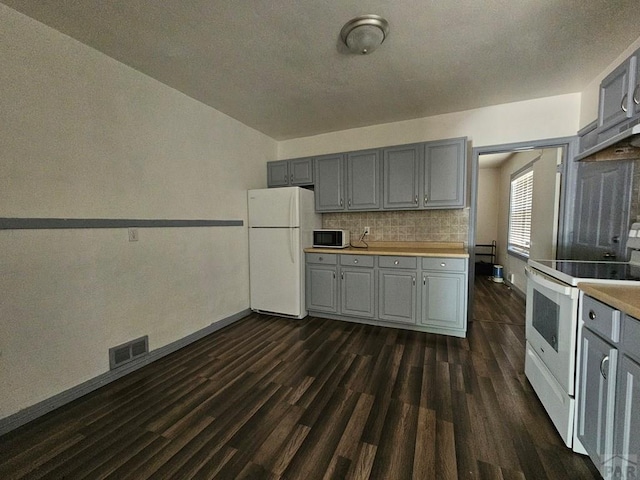 kitchen featuring white appliances, visible vents, dark wood finished floors, light countertops, and gray cabinetry