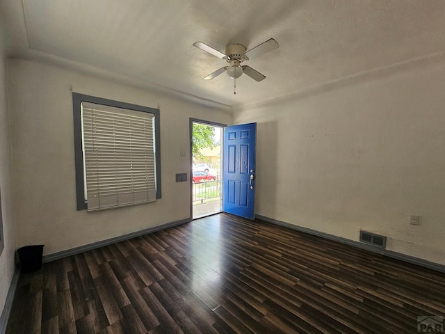 empty room featuring baseboards, dark wood-type flooring, visible vents, and a ceiling fan