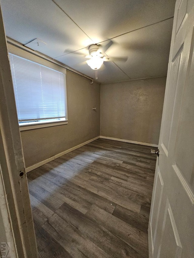 spare room featuring dark wood finished floors, baseboards, and ceiling fan