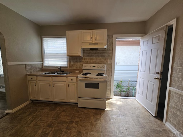 kitchen featuring electric range, white cabinets, decorative backsplash, under cabinet range hood, and a sink