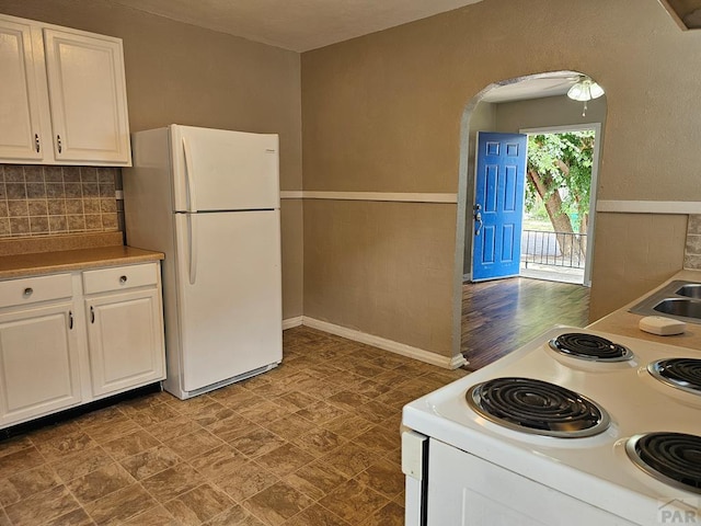 kitchen featuring white appliances, white cabinetry, arched walkways, and backsplash