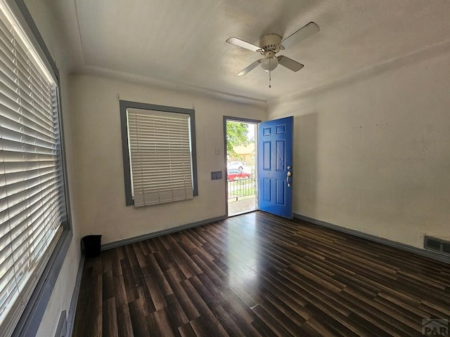 empty room featuring dark wood-style floors, baseboards, visible vents, and a ceiling fan