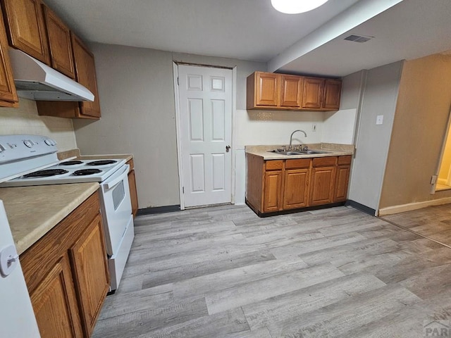 kitchen with light countertops, white electric stove, under cabinet range hood, and a sink