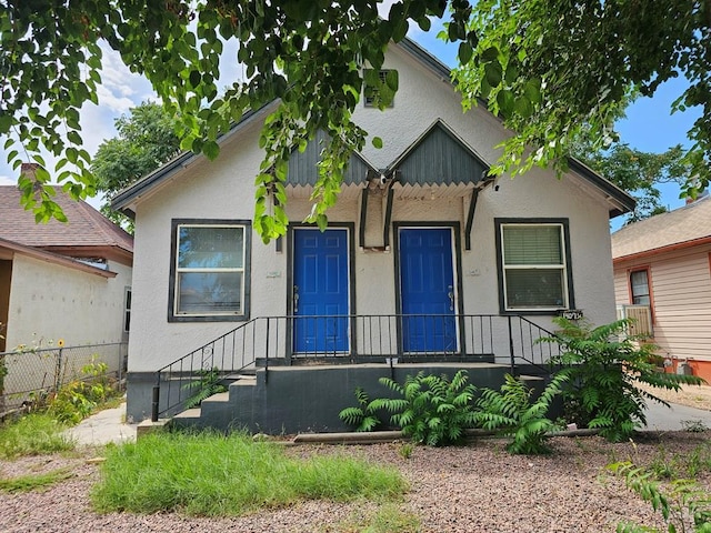 bungalow-style house with fence and stucco siding