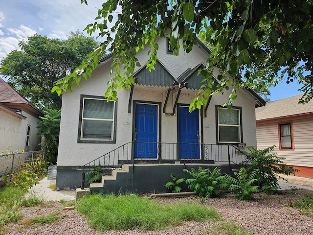 bungalow-style house featuring fence and stucco siding