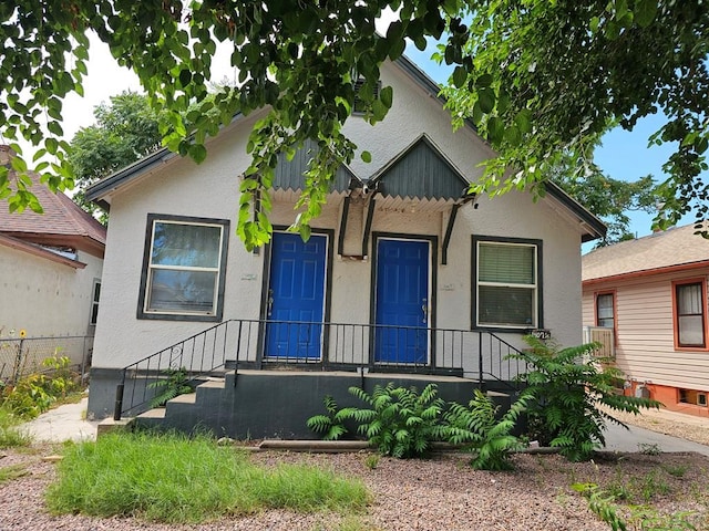 bungalow with fence and stucco siding