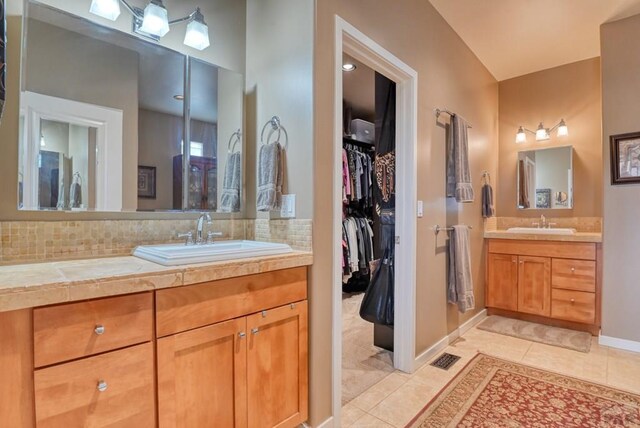 bathroom with tile patterned flooring, visible vents, vanity, backsplash, and a walk in closet