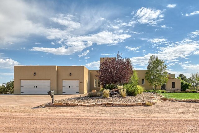 southwest-style home featuring a garage, concrete driveway, and stucco siding