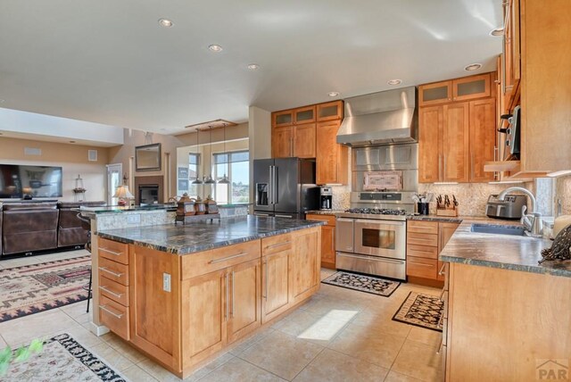 kitchen featuring a center island, wall chimney exhaust hood, a sink, double oven range, and high end refrigerator