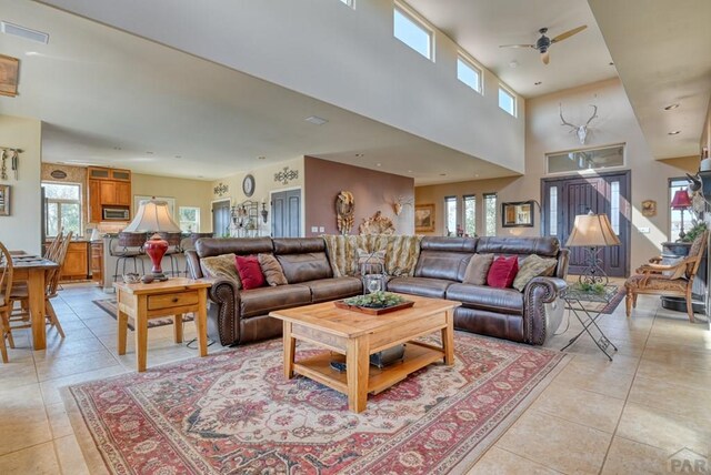 living room featuring visible vents, ceiling fan, a high ceiling, and light tile patterned floors