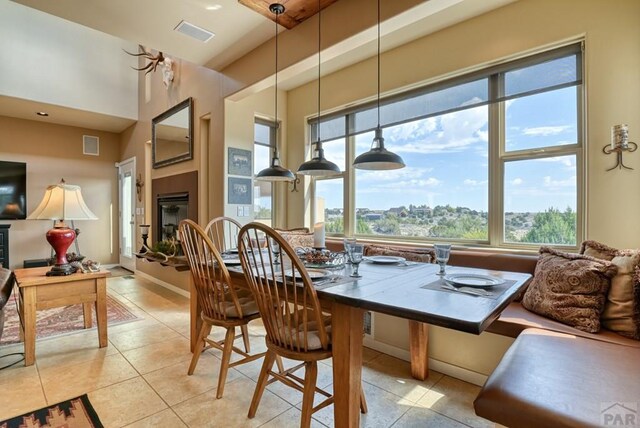 dining room featuring baseboards, visible vents, a glass covered fireplace, and light tile patterned flooring