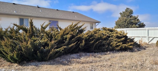 view of side of property with roof with shingles and fence