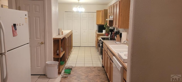 kitchen with pendant lighting, light tile patterned floors, light countertops, a sink, and white appliances