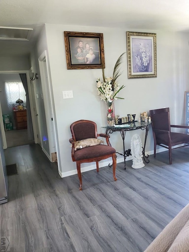 living area with visible vents, baseboards, and wood finished floors