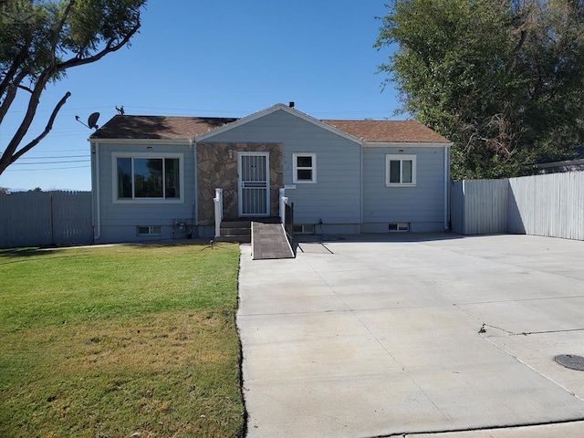 view of front facade featuring stone siding, fence, and a front lawn