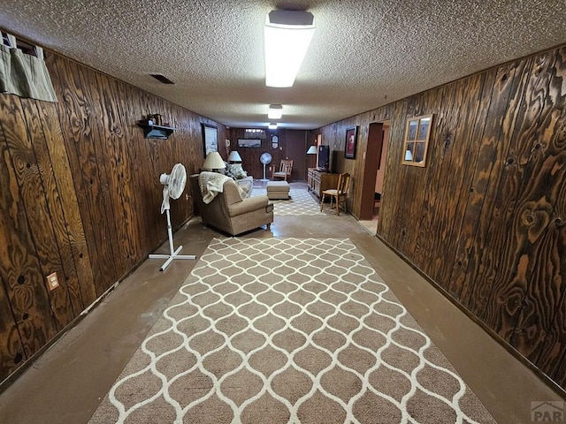 103 S Goff St, Eads, CO 81036 - living room with wood walls, a textured ceiling, and concrete floors