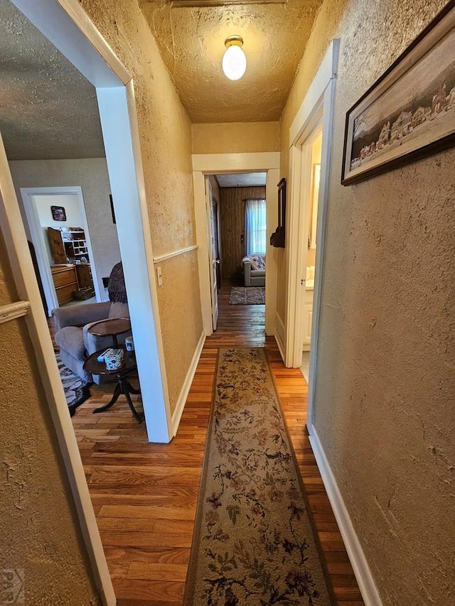 103 S Goff St, Eads, CO 81036 - hallway featuring wood finished floors, a textured wall, a textured ceiling, and baseboards