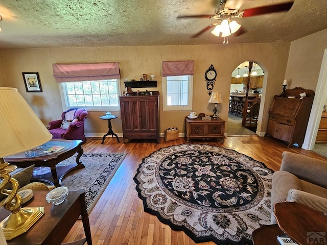 103 S Goff St, Eads, CO 81036 - living area with hardwood / wood-style floors, a ceiling fan, a textured ceiling, arched walkways, and baseboards