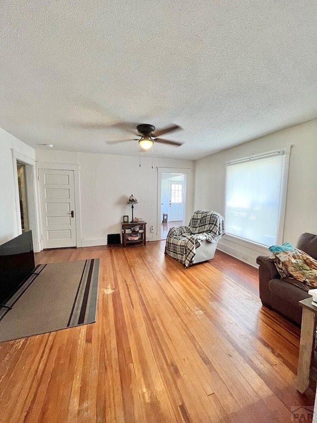 living area featuring ceiling fan, a textured ceiling, and wood finished floors