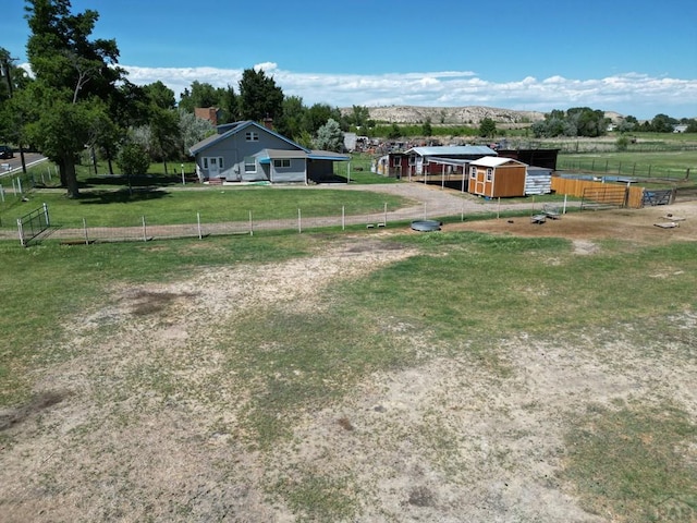 view of yard featuring an outbuilding, a rural view, a mountain view, fence, and an exterior structure