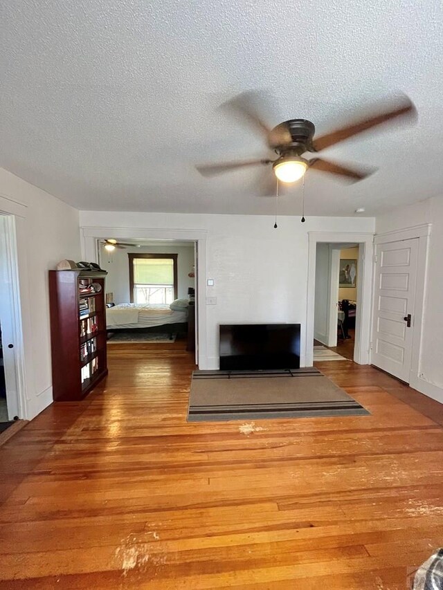 unfurnished living room with ceiling fan, a textured ceiling, and light wood finished floors