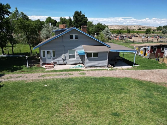 back of property with entry steps, a mountain view, a yard, driveway, and a carport