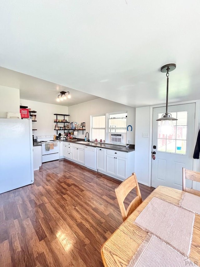 kitchen with white appliances, dark wood finished floors, dark countertops, white cabinetry, and pendant lighting